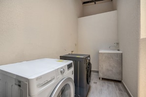 A laundry area with a washing machine, dryer, and a small sink. - Housy Laureles - 204 (Medellín)