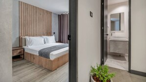 A modern bedroom with a wooden headboard, a bed with white bedding, a nightstand, and a potted plant.