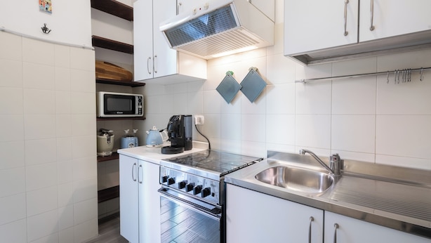 Uma cozinha moderna com armários brancos, eletrodomésticos de aço inoxidável e forno embutido.