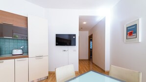 Una cocina moderna con un televisor de pantalla plana, una mesa de comedor con sillas y un cuadro en la pared.