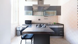 A modern kitchen with a central island, stainless steel appliances, and a microwave. - Casa Aosta (Rome)
