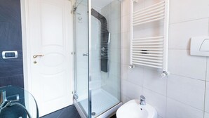 A modern bathroom with a glass-enclosed shower, a white sink, and a towel rack. - Casa Aosta (Rome)