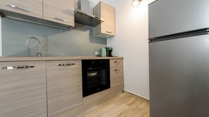 Cuina moderna amb forn de mur, electrodomèstics d'acer inoxidable i armaris de fusta clara.
