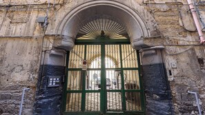 An arched entrance with a green gate, a security keypad, and a barred window. - Vico Sedil Capuano 21 (Naples)