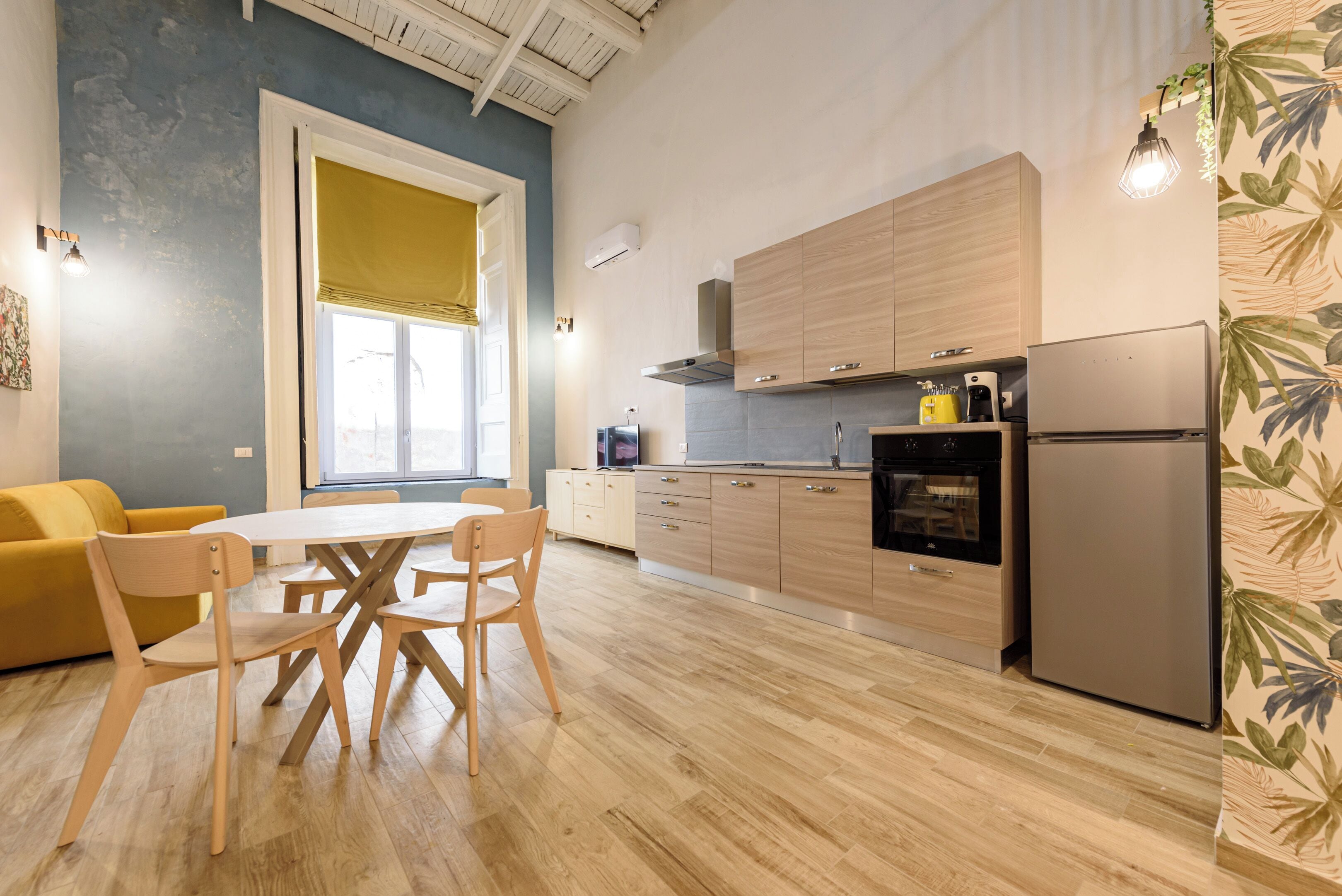 Una cocina moderna con armarios de madera, un refrigerador de acero inoxidable y un comedor con mesa y sillas.
