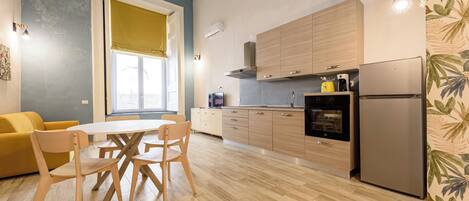 Una cocina moderna con armarios de madera, un refrigerador de acero inoxidable y un comedor con mesa y sillas.
