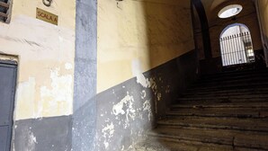 Una escalera con pintura descascarada y una reja metálica en la parte superior.