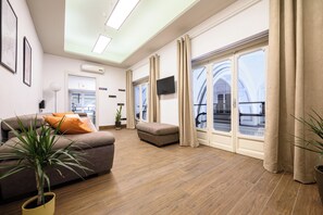 A spacious living room with a sofa, ottoman, and potted plants. - Piazza Nicola Amore 14 (Naples)