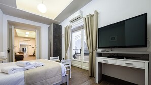 A hotel room with a bed, a desk with a flat-screen TV, a chair, and a window with curtains. - Piazza Nicola Amore 14 (Naples)