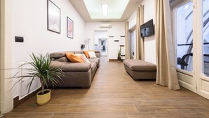 A modern living room with a sofa, a potted plant, and a television. - Piazza Nicola Amore 14 (Naples)