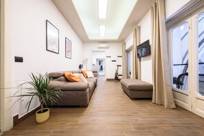 Ein modernes Wohnzimmer mit einer Couch, einem Blumentopf und einem Fernseher.