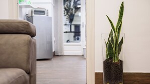 A living room with a brown sofa, a glass vase with a plant, and a kitchen area in the background. - Piazza Nicola Amore 14 (Naples)