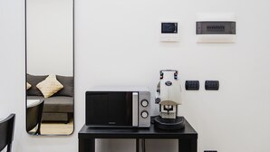 A modern room with a large mirror, a microwave, a coffee machine, and a small table. - Via Niccolò Tommaseo 4 - Appartamento 4 (Naples)