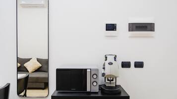 Una camera moderna con uno specchio grande, un forno a microonde, una macchina per il caffè e un tavolino.