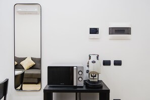 Ein modernes Zimmer mit einem großen Spiegel, einer Mikrowelle, einer Kaffeemaschine und einem kleinen Tisch.