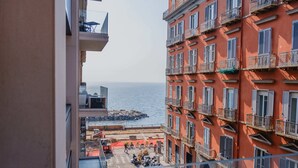 A multi-story building with balconies, a view of the sea, and a street with parked motorcycles. - Via Niccolò Tommaseo 4 - Appartamento 4 (Naples)