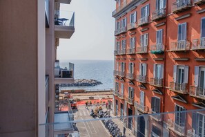 Ein mehrstöckiges Gebäude mit Balkonen, Blick auf das Meer und eine Straße mit abgestellten Motorrädern.