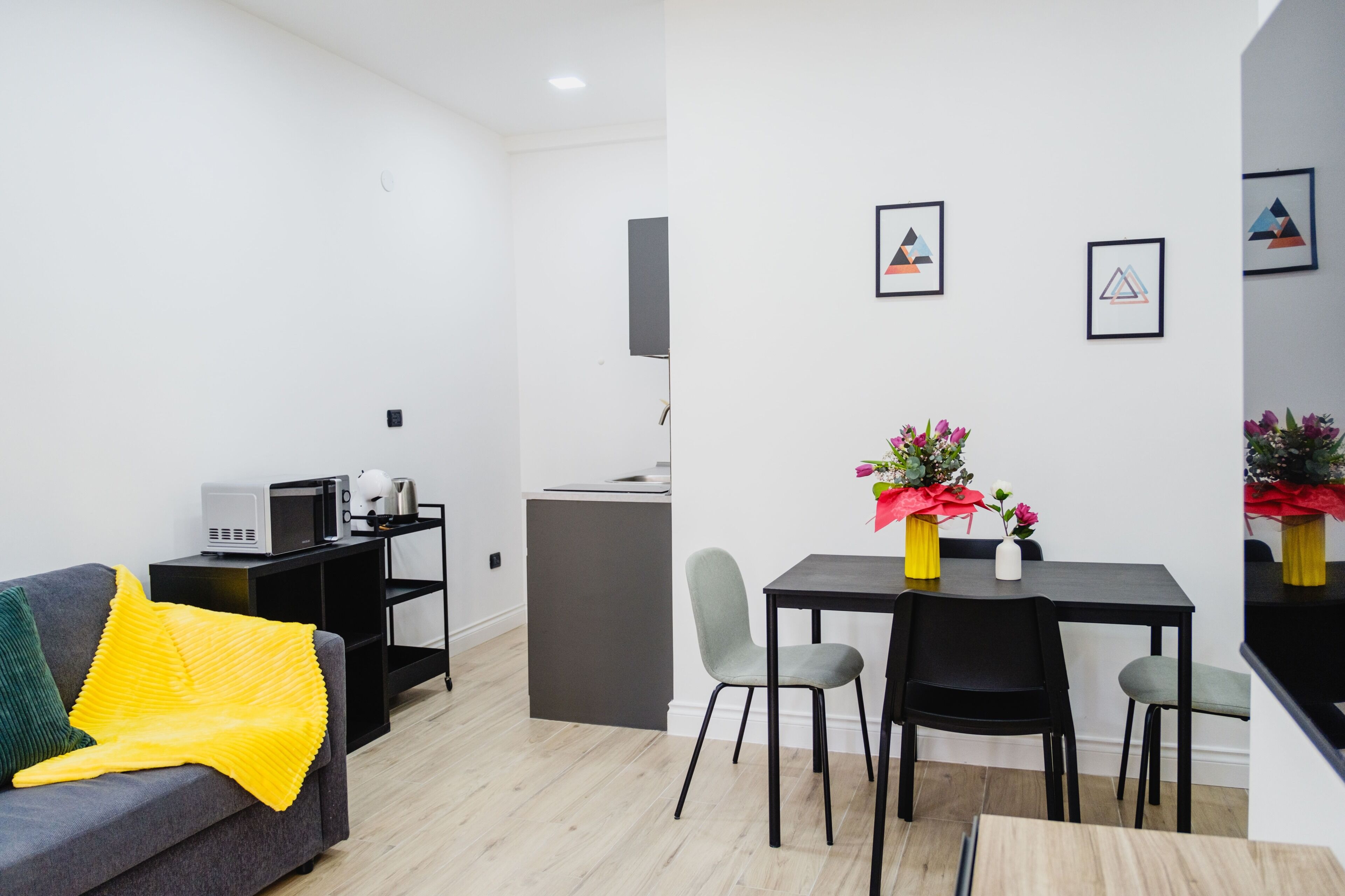 Een moderne woonkamer met een bank, een eettafel met stoelen, een keuken en een klein barretje.