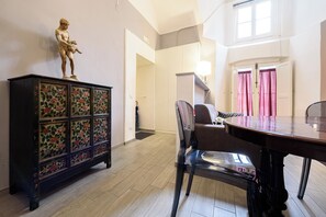 A dining area with a wooden table and chairs, a decorative cabinet with floral patterns, and a statue on top. - Via Atri 37 (Naples)