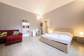 A modern bedroom with a bed, a red sofa, a bookshelf, and a desk. - Via Atri 37 (Naples)