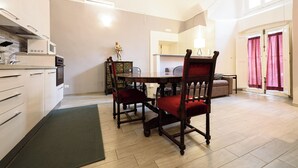 A modern kitchen with white cabinets, a dining table with red chairs, and a large window with curtains. - Via Atri 37 (Naples)
