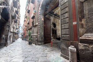 A narrow cobblestone street flanked by historic buildings with balconies and a wooden door. - Via Atri 37 (Naples)