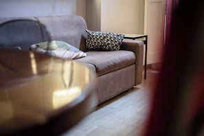 A modern living room with a sofa, a patterned pillow, and a round coffee table. - Via Atri 37 (Naples)