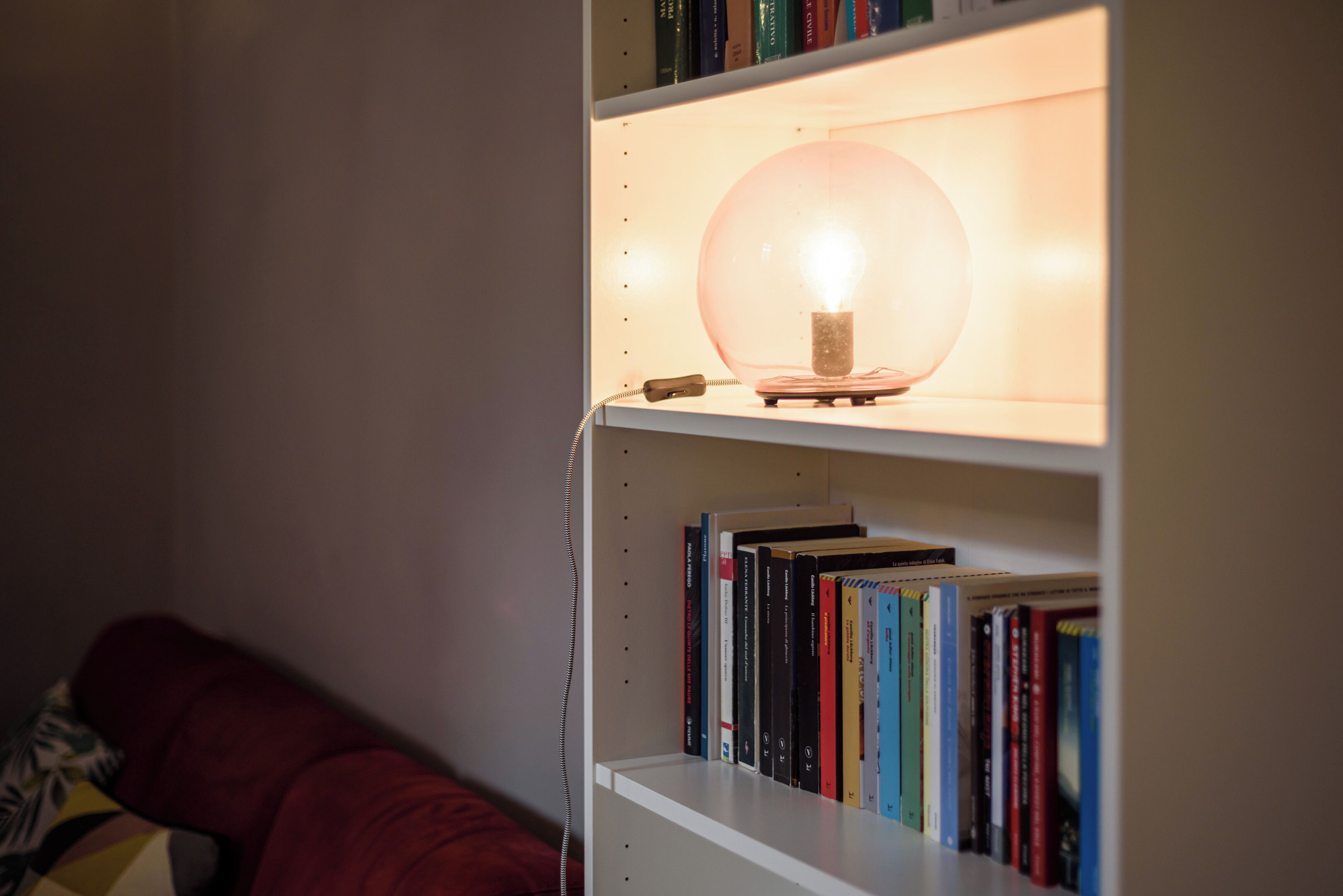 Ein Bücherregal mit einer Kugelleuchte und Büchern.