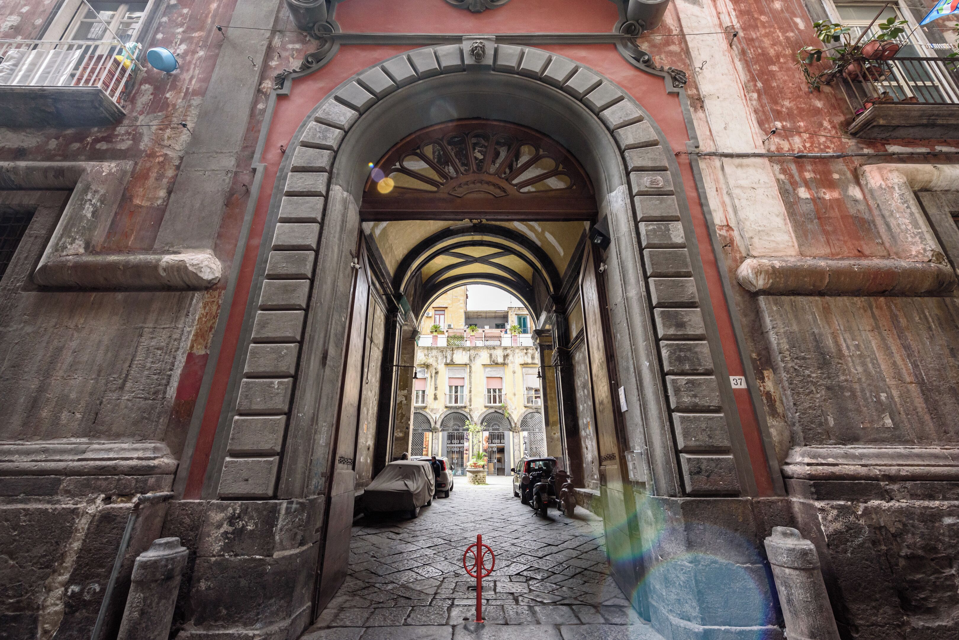 An arched entrance with a cobblestone path leading to a building.