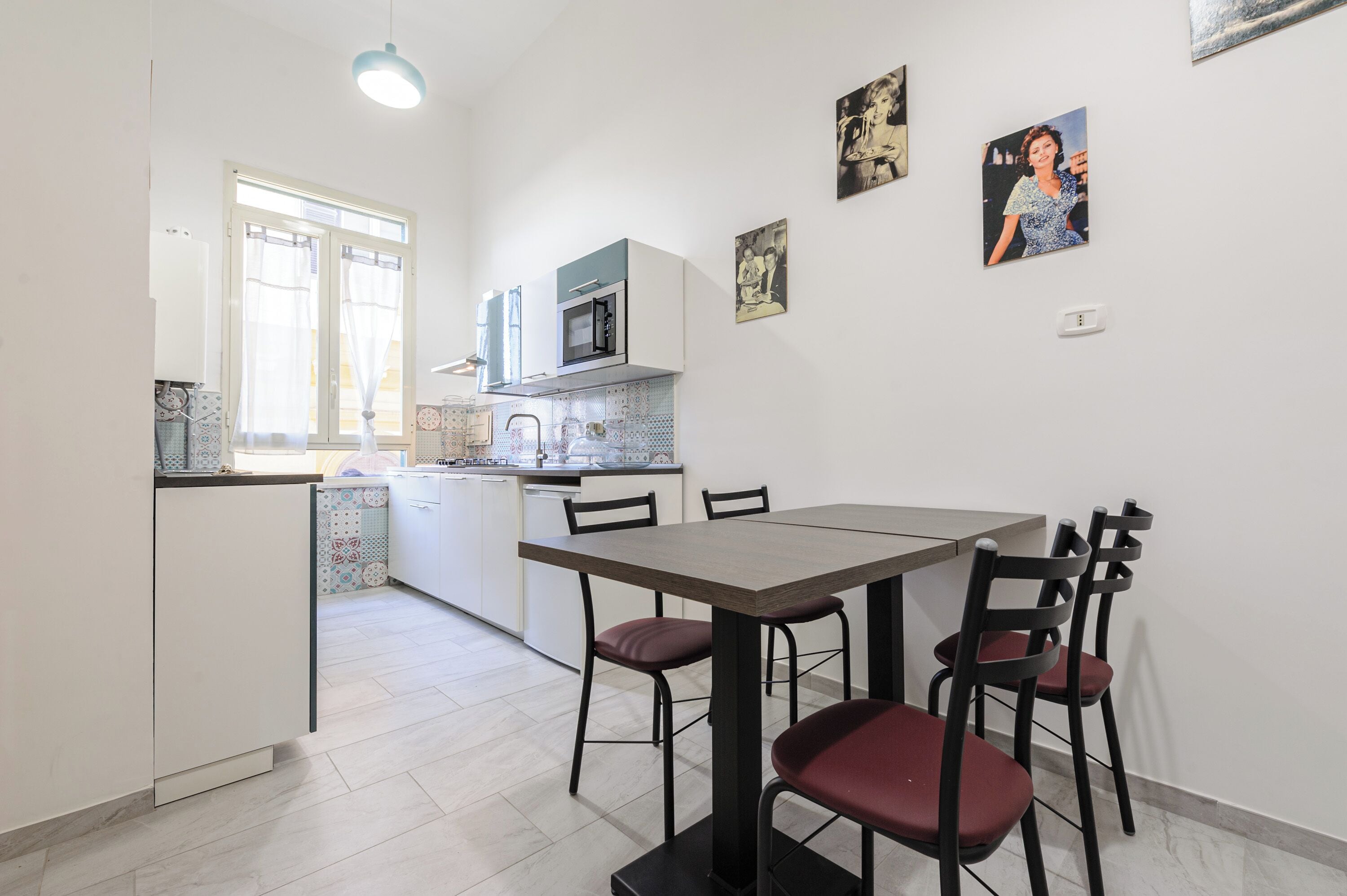 A compact kitchen with a dining area, featuring a microwave, cabinets, and a tiled backsplash.