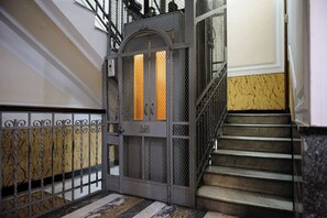 A metal gate with a decorative design, a staircase with a handrail, and a marble floor. - Via Aniello Falcone 72b (Naples)
