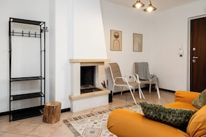 Una sala de estar con chimenea, perchero, sillón y sofá.