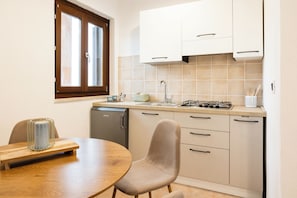 Una cocina compacta con una mesa de comedor, sillas, lavavajillas y una ventana.