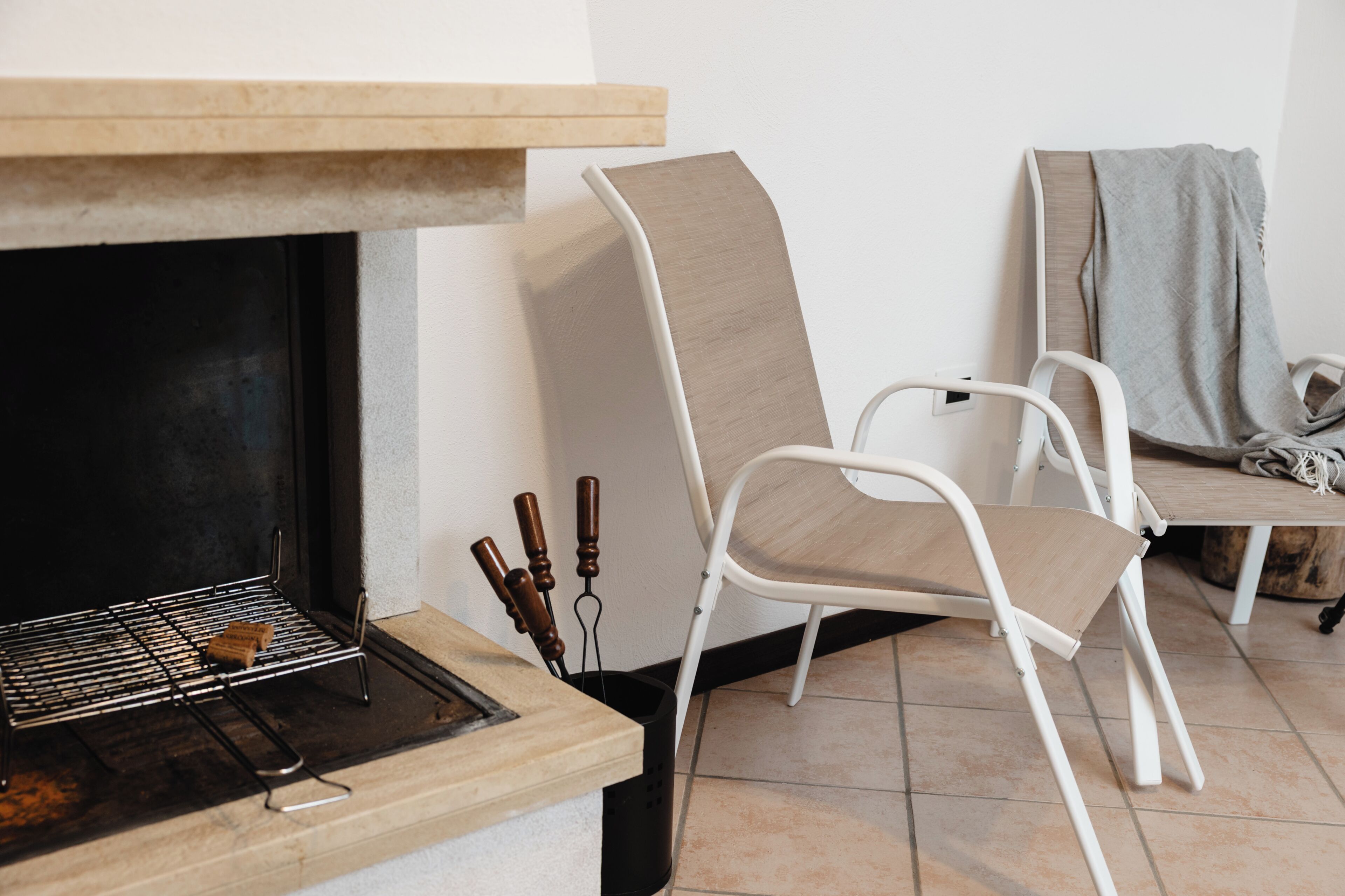 Una habitación con una parrilla, una silla blanca y una mesa de madera.