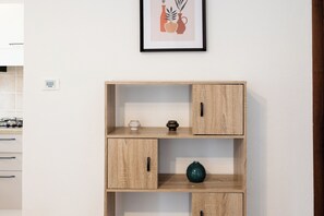 Un mueble de madera con dos puertas y dos cajones, un jarrón pequeño y un cuadro en la pared.