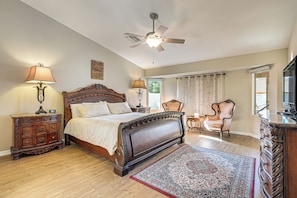 Ein Schlafzimmer mit Bett, Kommode, Nachttisch, Stuhl und Deckenventilator.