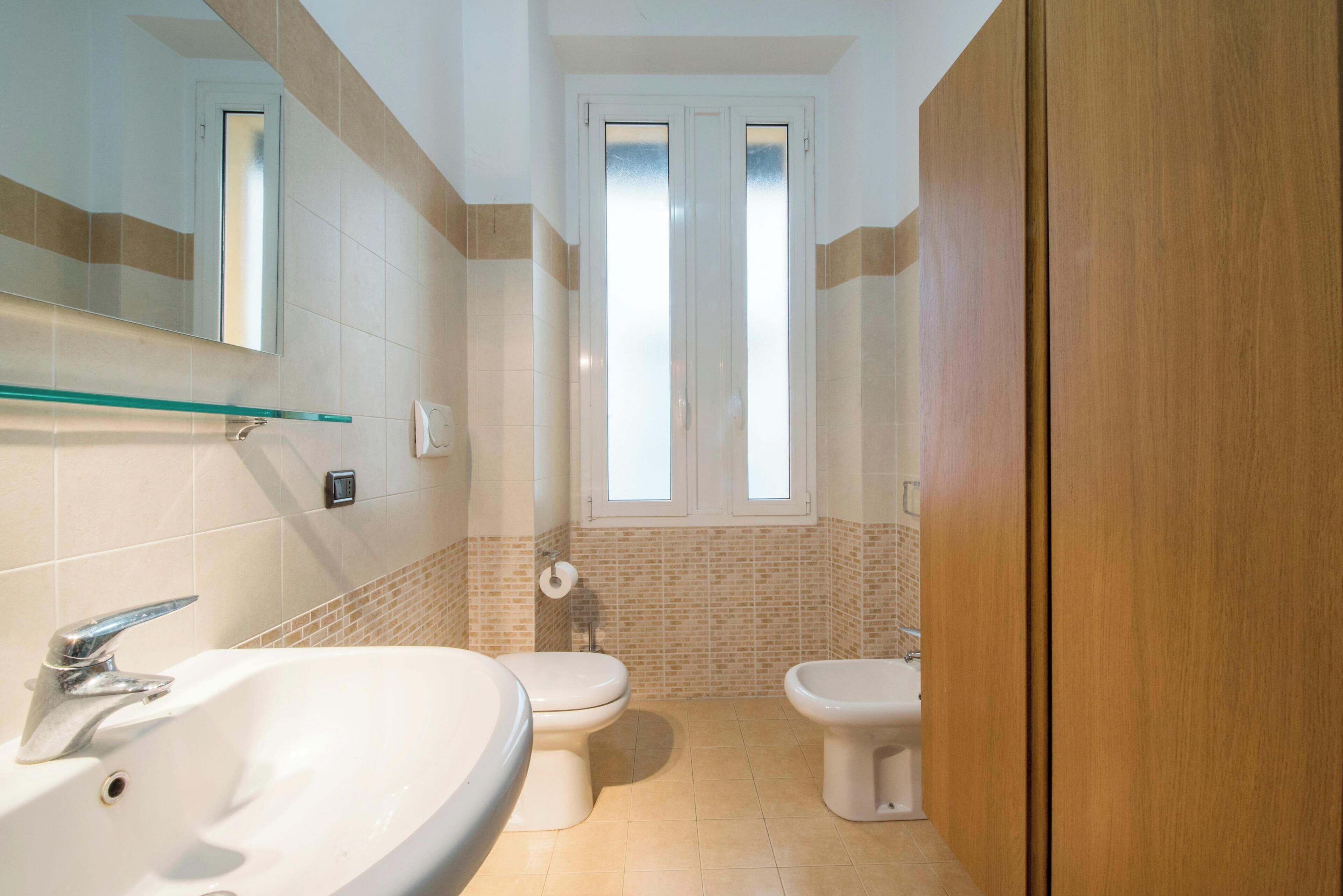 Un baño con lavamanos, inodoro, bidé y espejo.