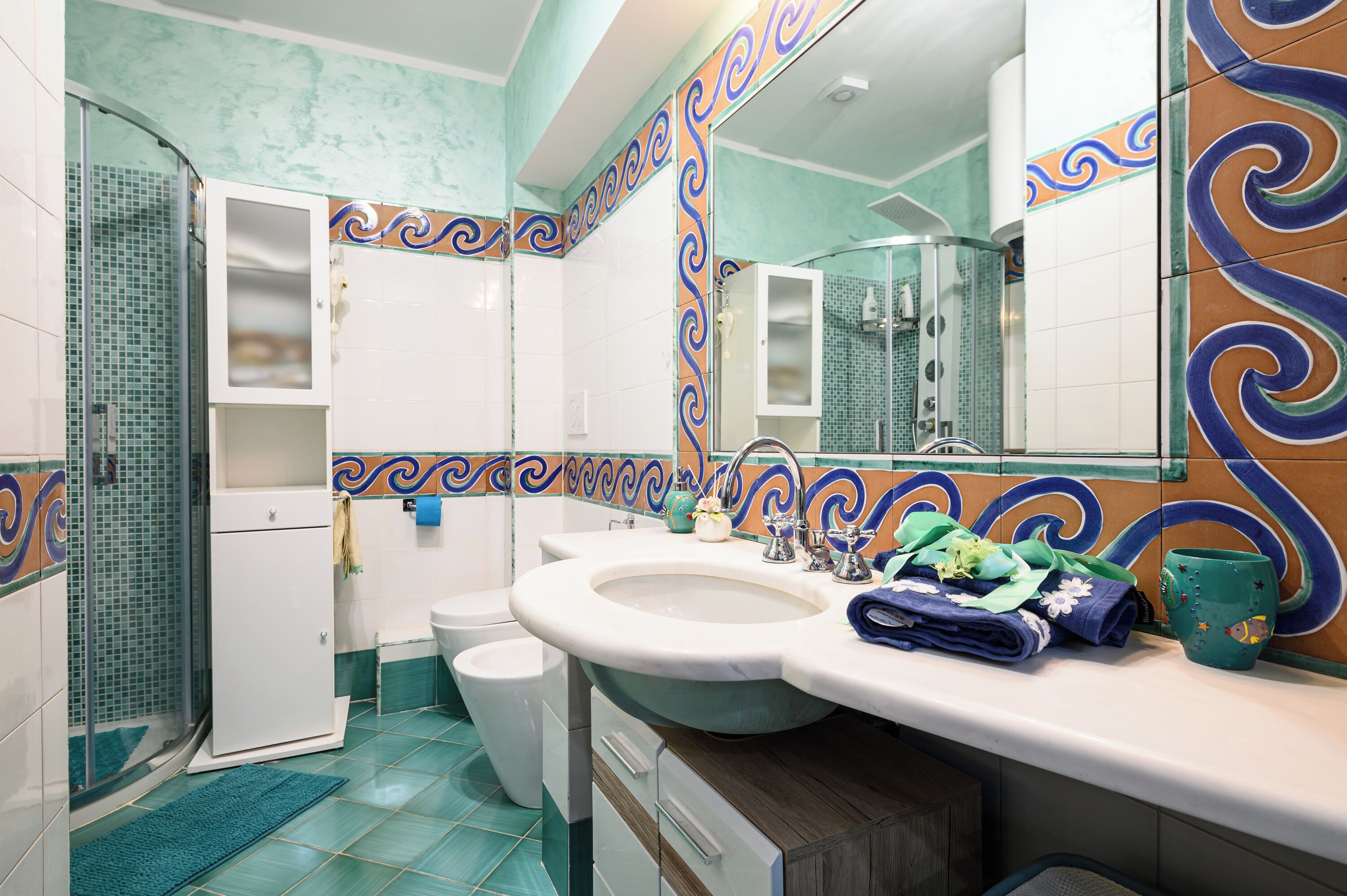Un baño con ducha, inodoro, lavamanos y un borde decorativo de azulejos.