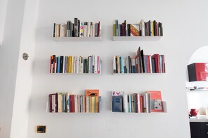 Eine Wand mit sechs Bücherregalen, in denen verschiedene Bücher und einige Dekoartikel stehen.
