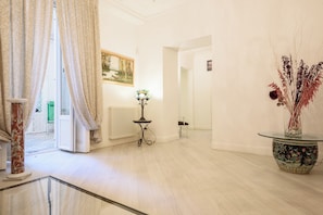 A spacious room with a large window, a radiator, a small table with a lamp, and a decorative vase with dried plants. - Palazzo Dello Spagnolo Suite (Naples)