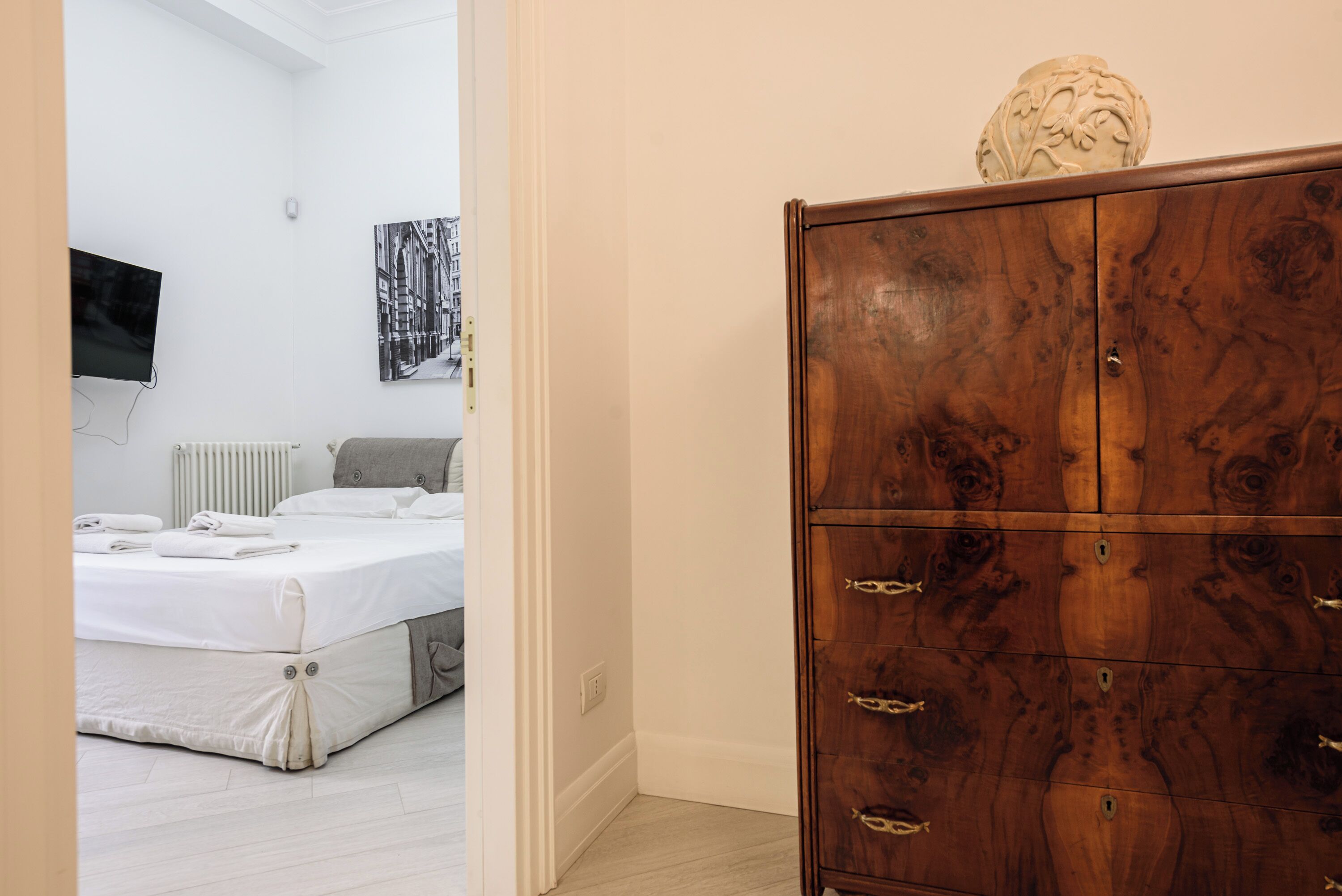 Hotelkamer met een bed, een houten garderobe, een televisie en een aan de muur hangend schilderij.