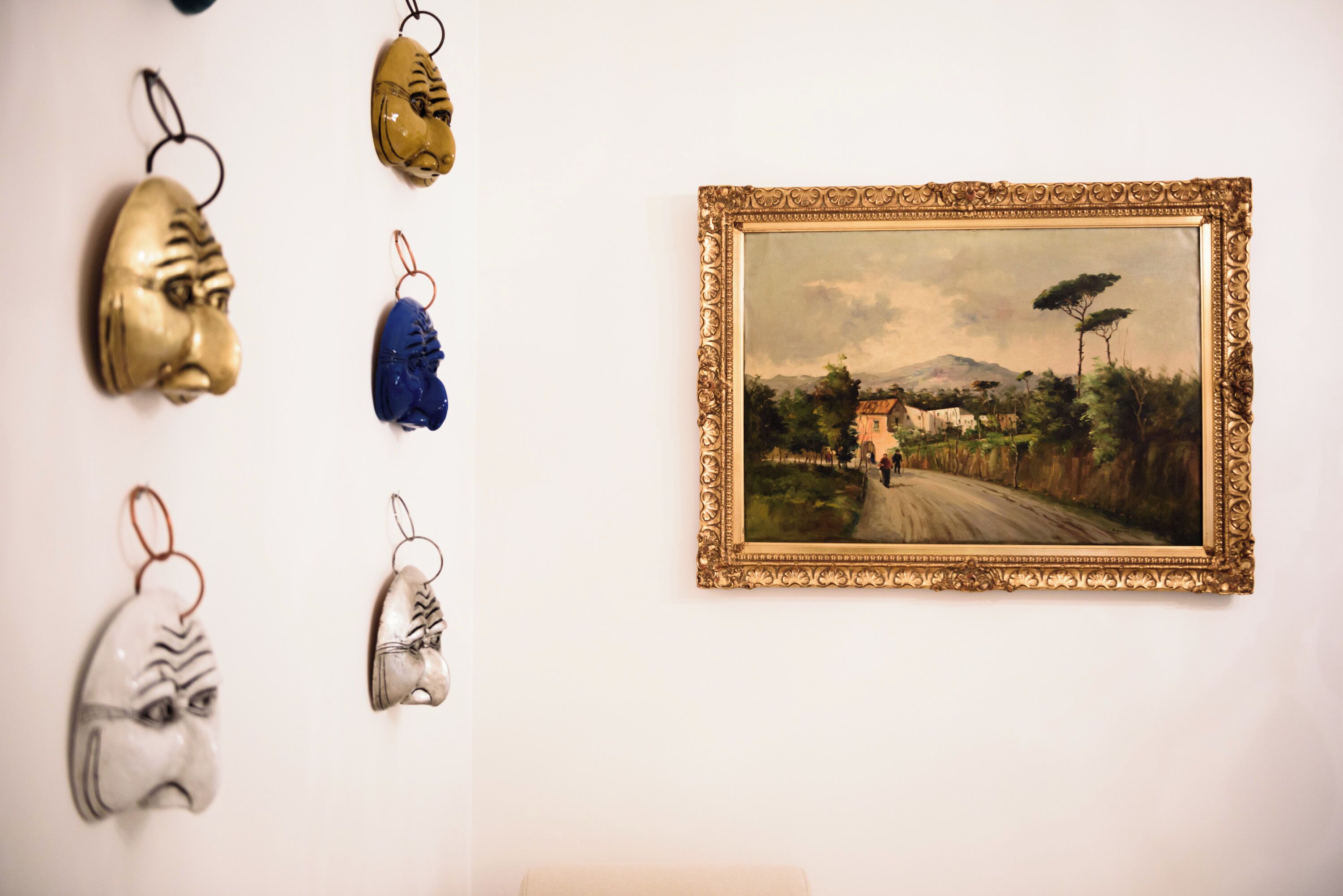 Un mur orné d’un tableau encadré représentant un paysage et de plusieurs décorations en forme de chaussures.