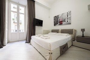 A bedroom with a bed, a TV, a nightstand, and a window with curtains. - Palazzo Dello Spagnolo Suite (Naples)