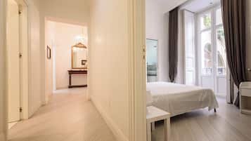 Una habitación de hotel con cama, mesita de noche, espejo y vistas al exterior a través de una ventana.