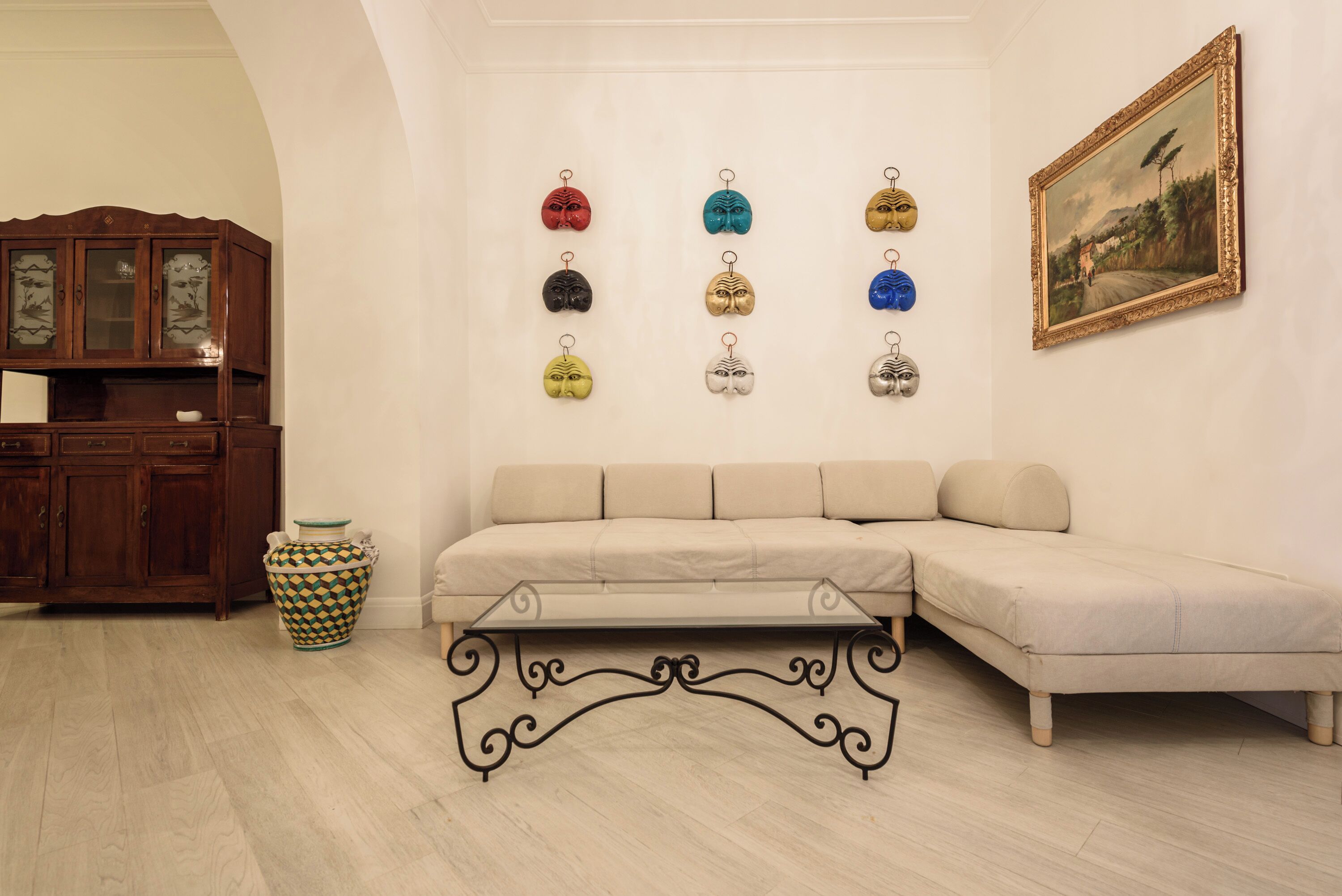 Un salon avec un canapé beige, un meuble en bois, un vase décoratif et un cadre photo fixé au mur.