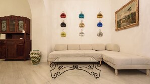 Ein Wohnzimmer mit einem beigefarbenen Sofa, einem Holzkabinett, einer dekorativen Vase und einem an der Wand befestigten Bilderrahmen.