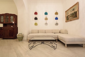 A living room with a beige sofa, a wooden cabinet, a decorative vase, and a wall-mounted picture frame. - Palazzo Dello Spagnolo Suite (Naples)