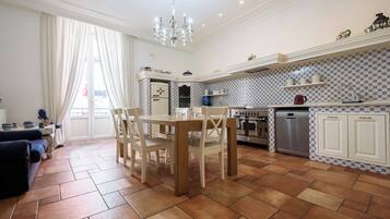 Een moderne keuken met een eethoek, met een kroonluchter, betegelde vloer en witte kasten.