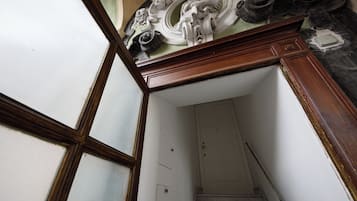 Una escalera que conduce a una puerta blanca, un marco de madera y un techo decorado con diseños intrincados.