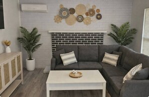 A living room with a grey sofa, white coffee table, and decorative wall art. - Cozy 1 bedroom Launch pad studio in Titusville near Kennedy space center (Titusville)